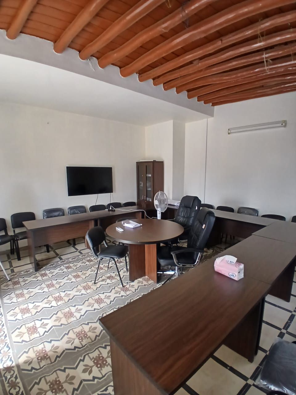 Meeting room with a round table, conference desks and a wall screen