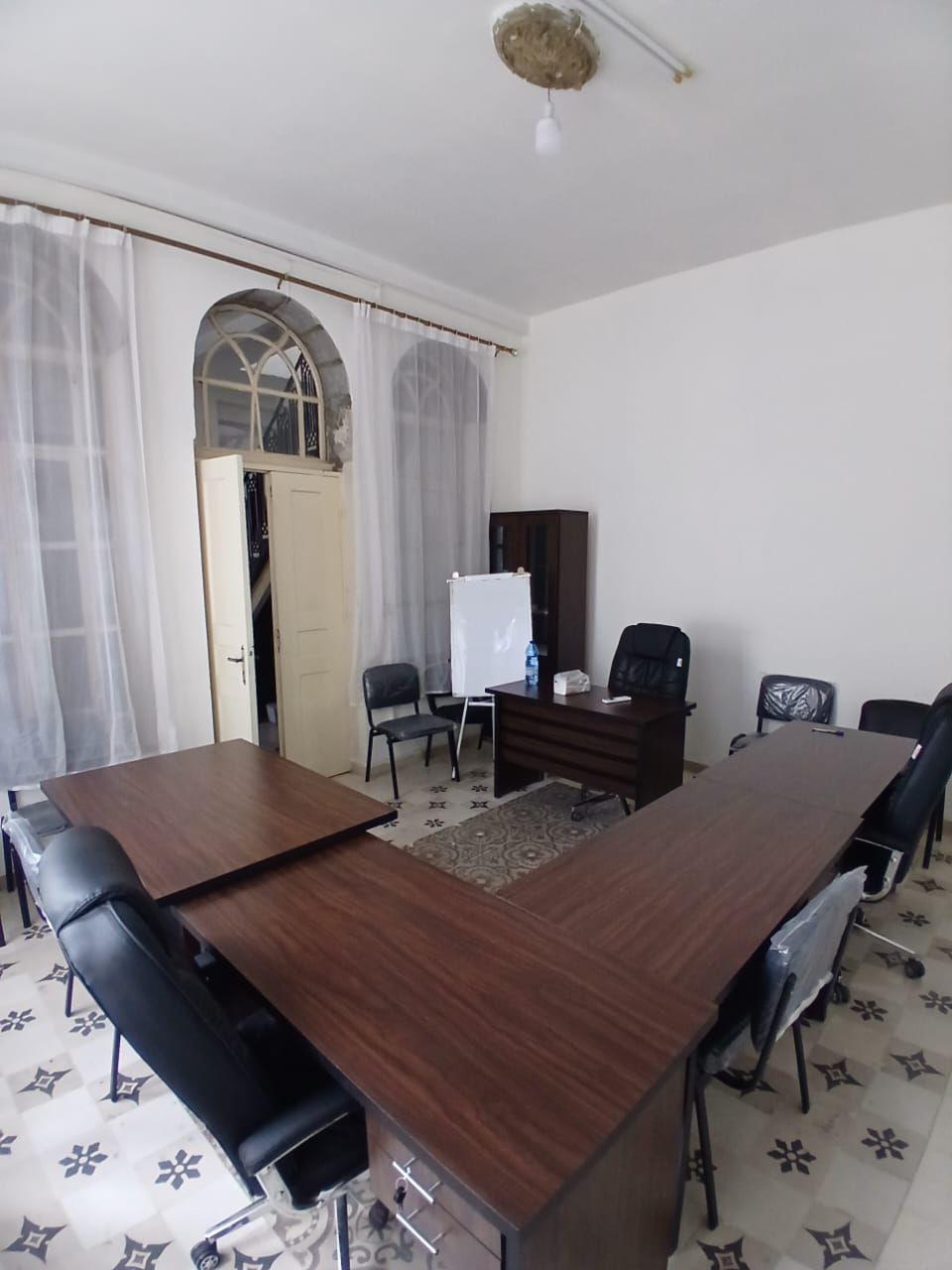 Room with L-shaped desks, office chairs and a flipchart