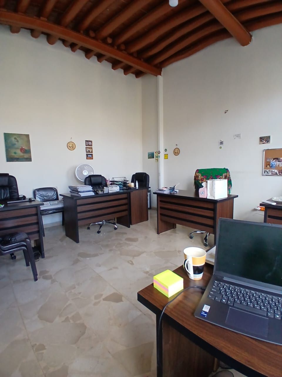 Office with several desks under a wooden-beamed ceiling